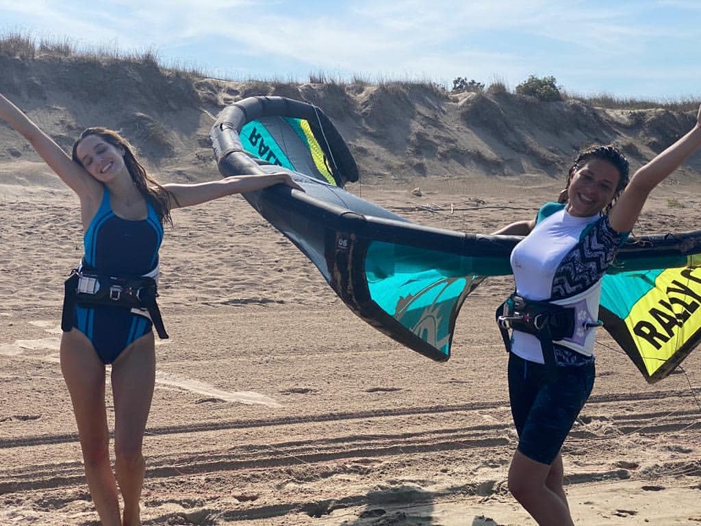 Chicas guapas levantando la cometa en la playa