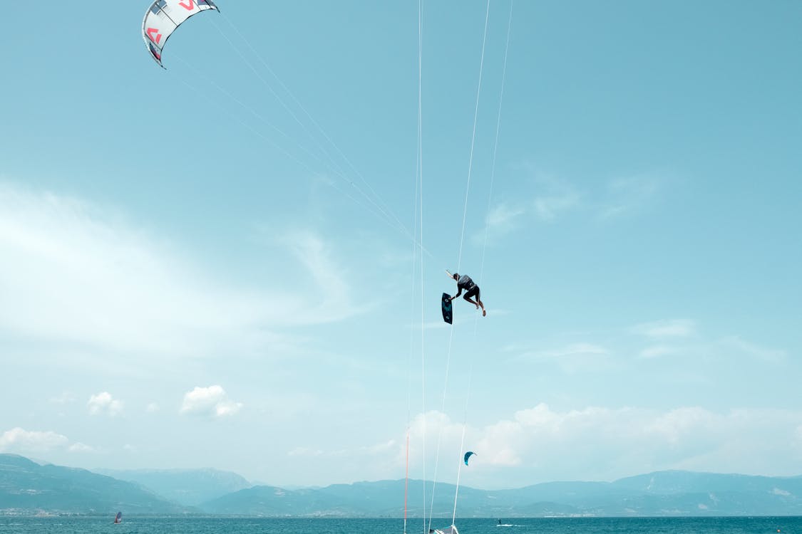 Kitesurfer haciendo un truco aéreo sobre el agua azul